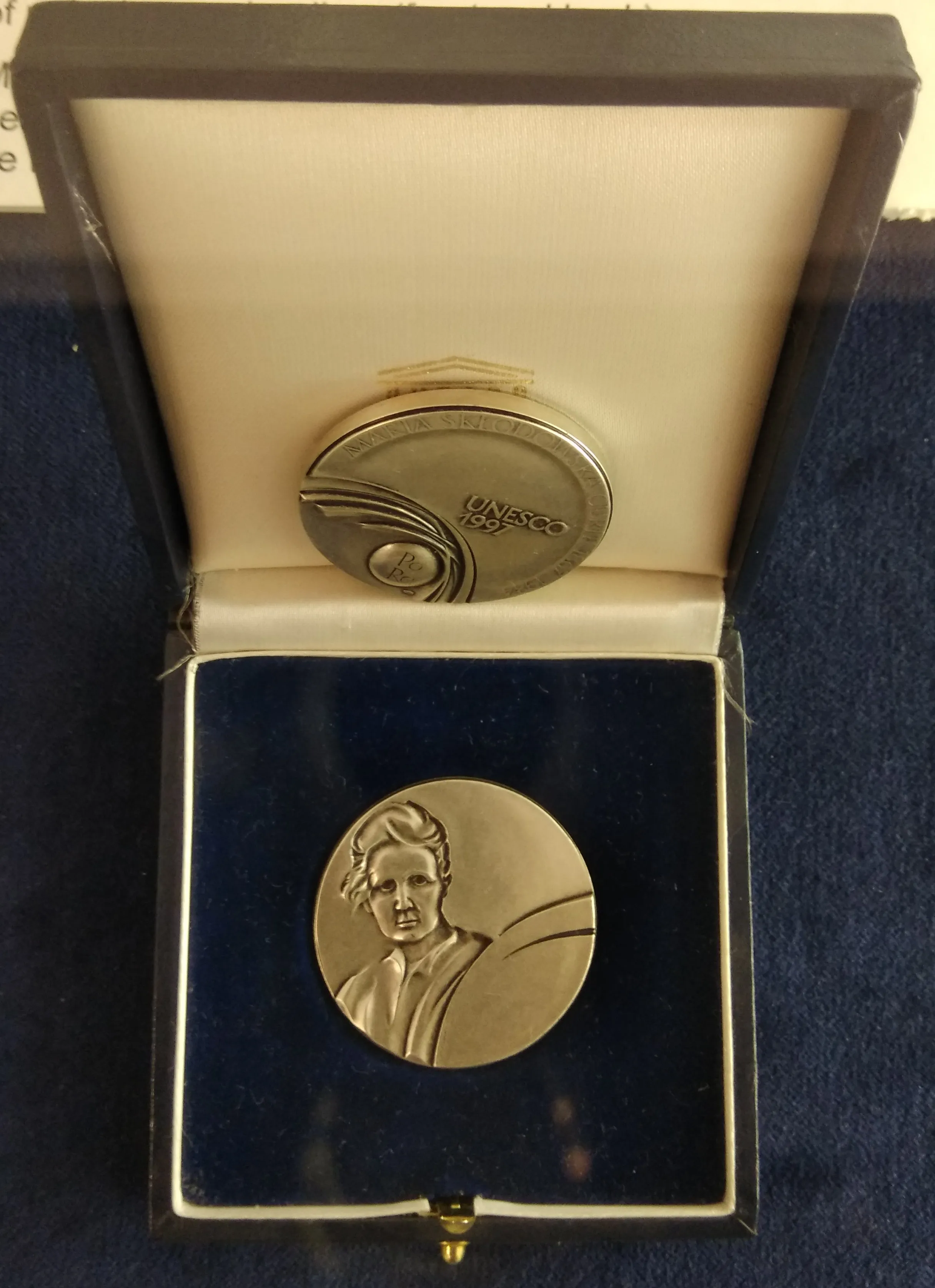 Srebrny medal z portretem kobiety w pudełku z niebieską aksamitną wyściółką