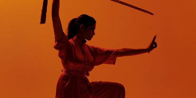 Silueta de un artista marcial en una postura dinámica sobre un fondo naranja intenso, con una espada visible sobre la figura