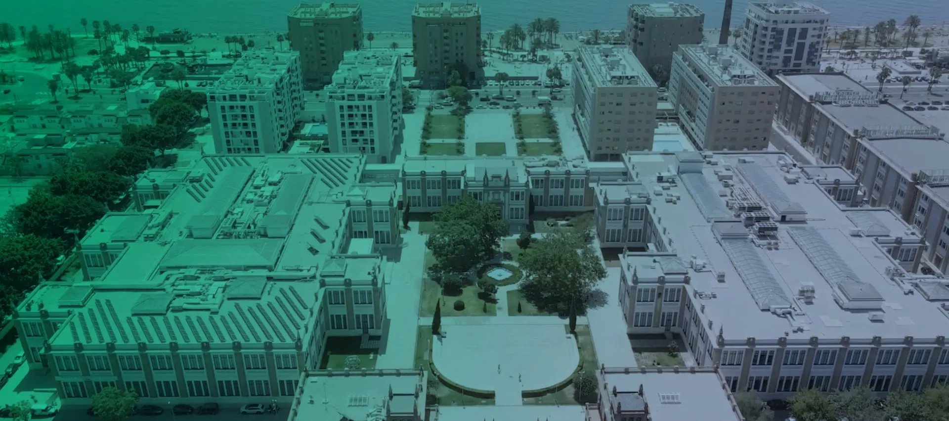Vista aérea cenital del complejo Tabacalera que muestra la disposición del gran edificio con un jardín central y las manzanas urbanas circundantes, renderizada con un marcado tono verdoso