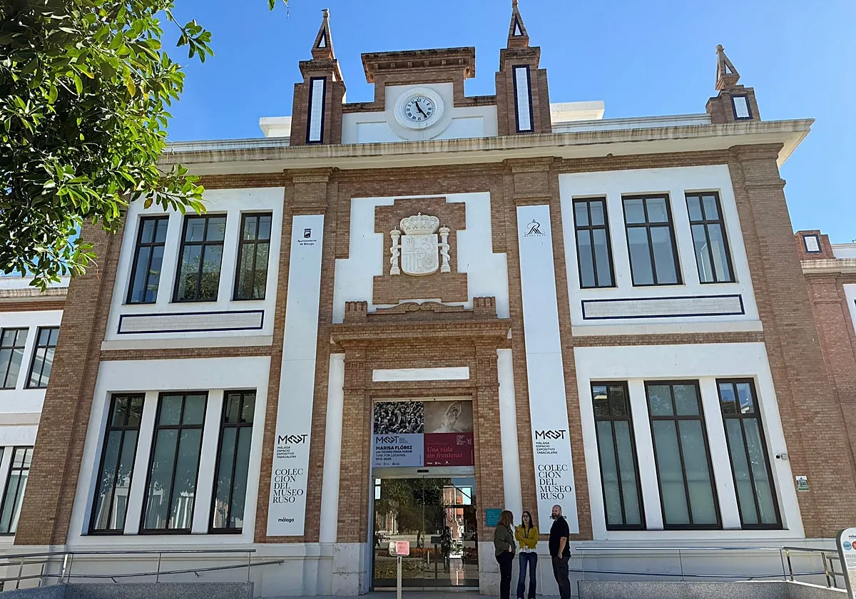 Fachada de ladrillo y color blanco del centro de exposiciones MEET Málaga con torre del reloj, escudo de armas y señalización en la entrada