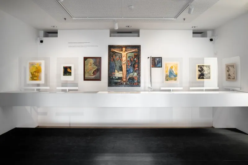 Kunstgalerie met een centraal kruisigingsschilderij en omringende kunstwerken op witte muren