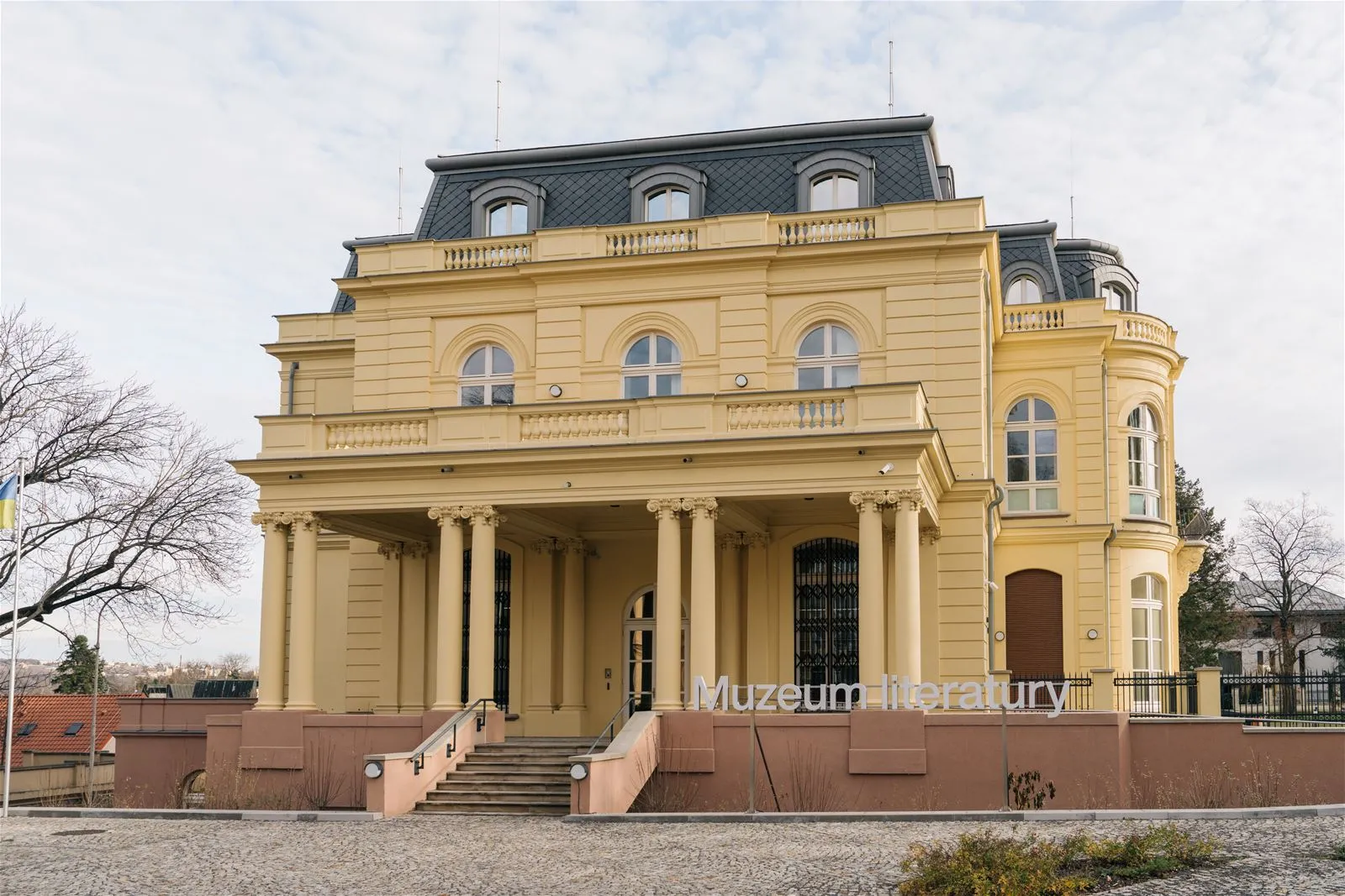 Geel neoklassiek gebouw met zuilen en boogvormige ramen, geïdentificeerd als het Museum van de Tsjechische Literatuur
