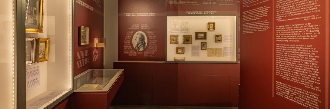 exposición de museo con documentos enmarcados y retratos en paredes rojas