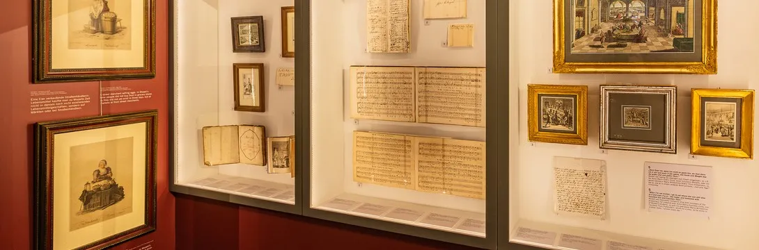 vitrinas de cristal con documentos enmarcados, manuscritos y retratos en una galería de museo