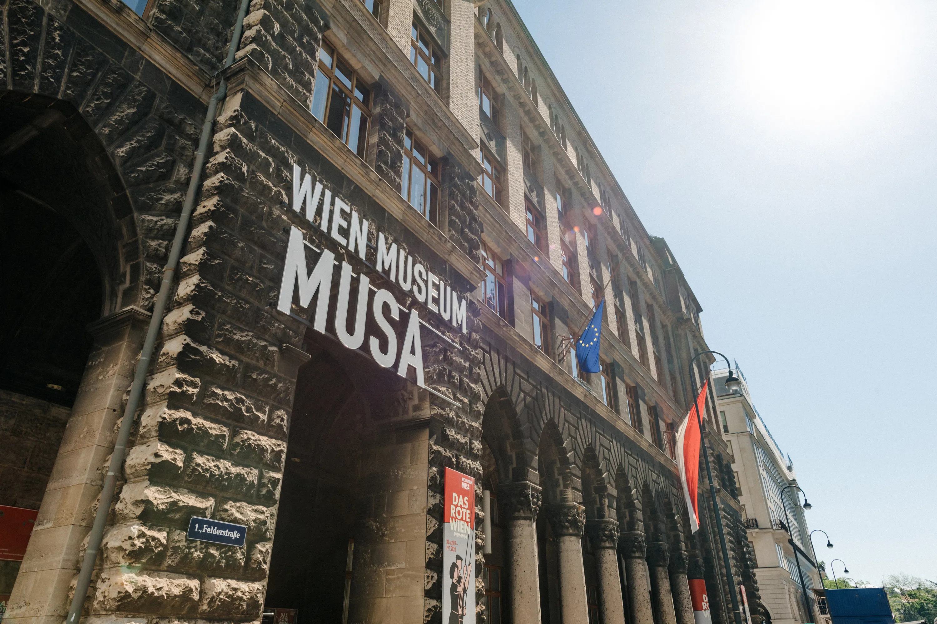 Stenen gebouw met boogvormige ingang en grote witte letters met de tekst WIEN MUSEUM MUSA op de gevel
