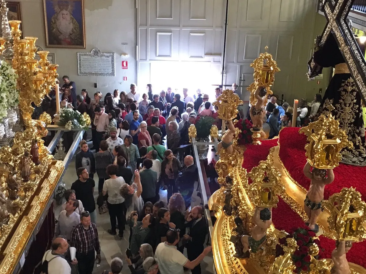 Vista en picado de una sala de museo llena de visitantes, flanqueada por ornamentados tronos procesionales dorados con terciopelo rojo y detalles metálicos intrincados.