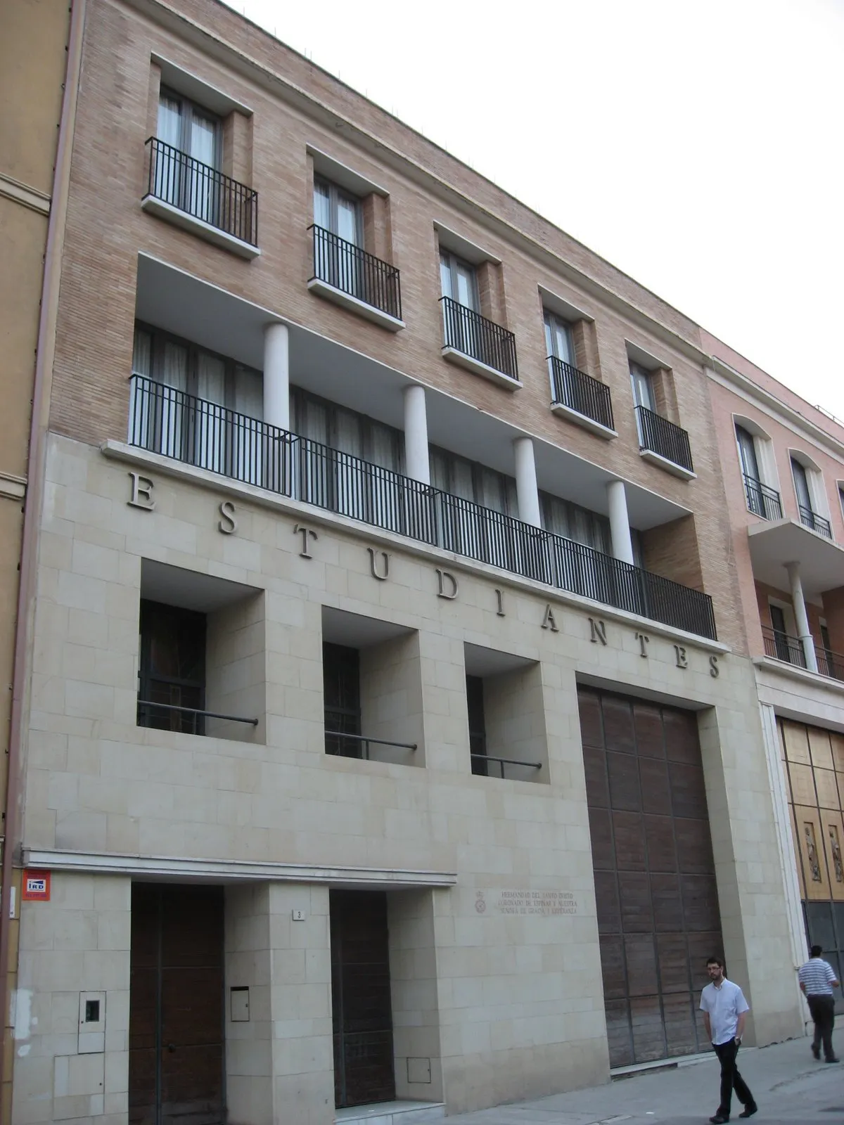 Fachada exterior del edificio del Museo de la Cofradía de Estudiantes con letras grandes que dicen ESTUDIANTES en el muro de piedra, balcones con barandillas de hierro, columnas blancas y una gran puerta de madera.
