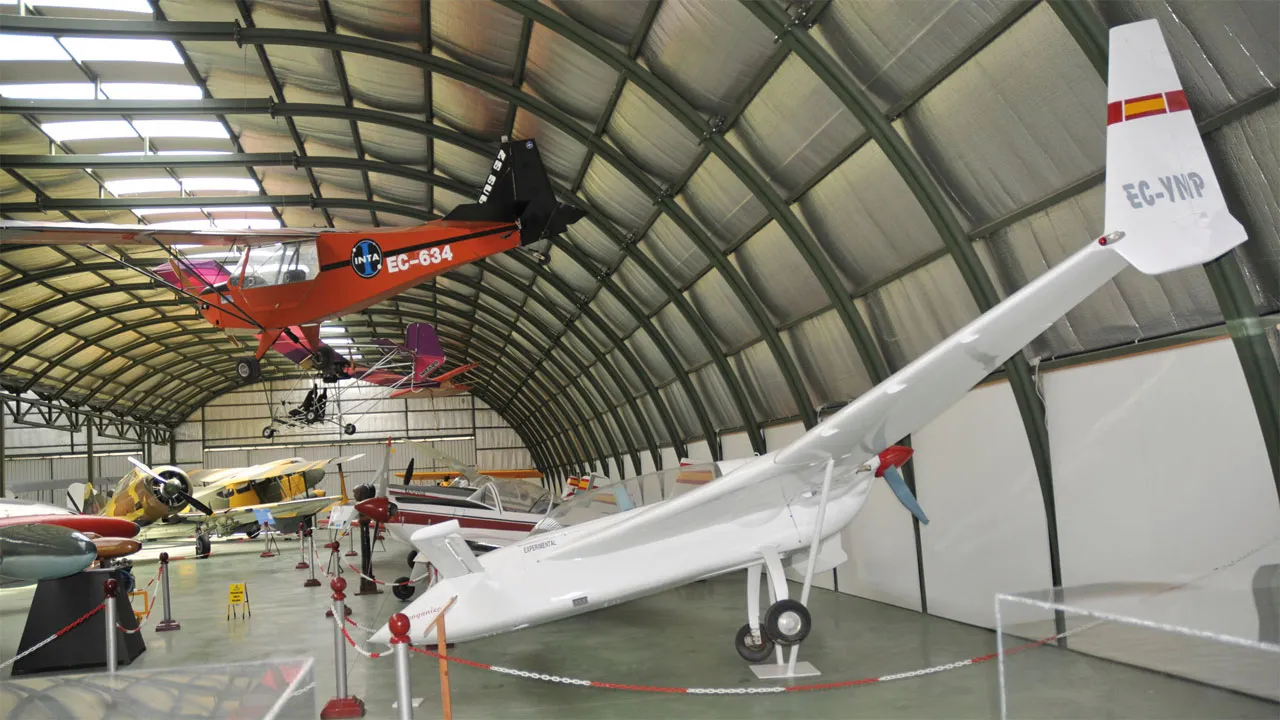 Wit vliegtuig tentoongesteld in een hangar met andere vliegtuigen op de achtergrond