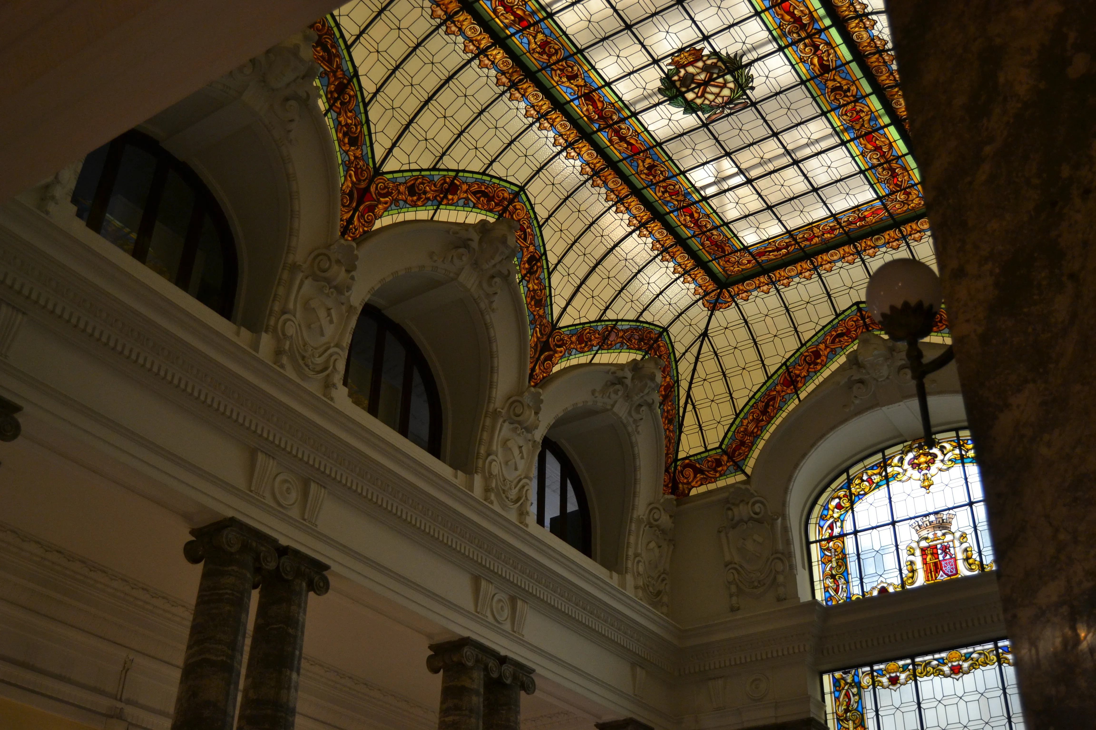 glazen plafond met kleurrijke patronen en sierlijke architectonische details in een grote hal