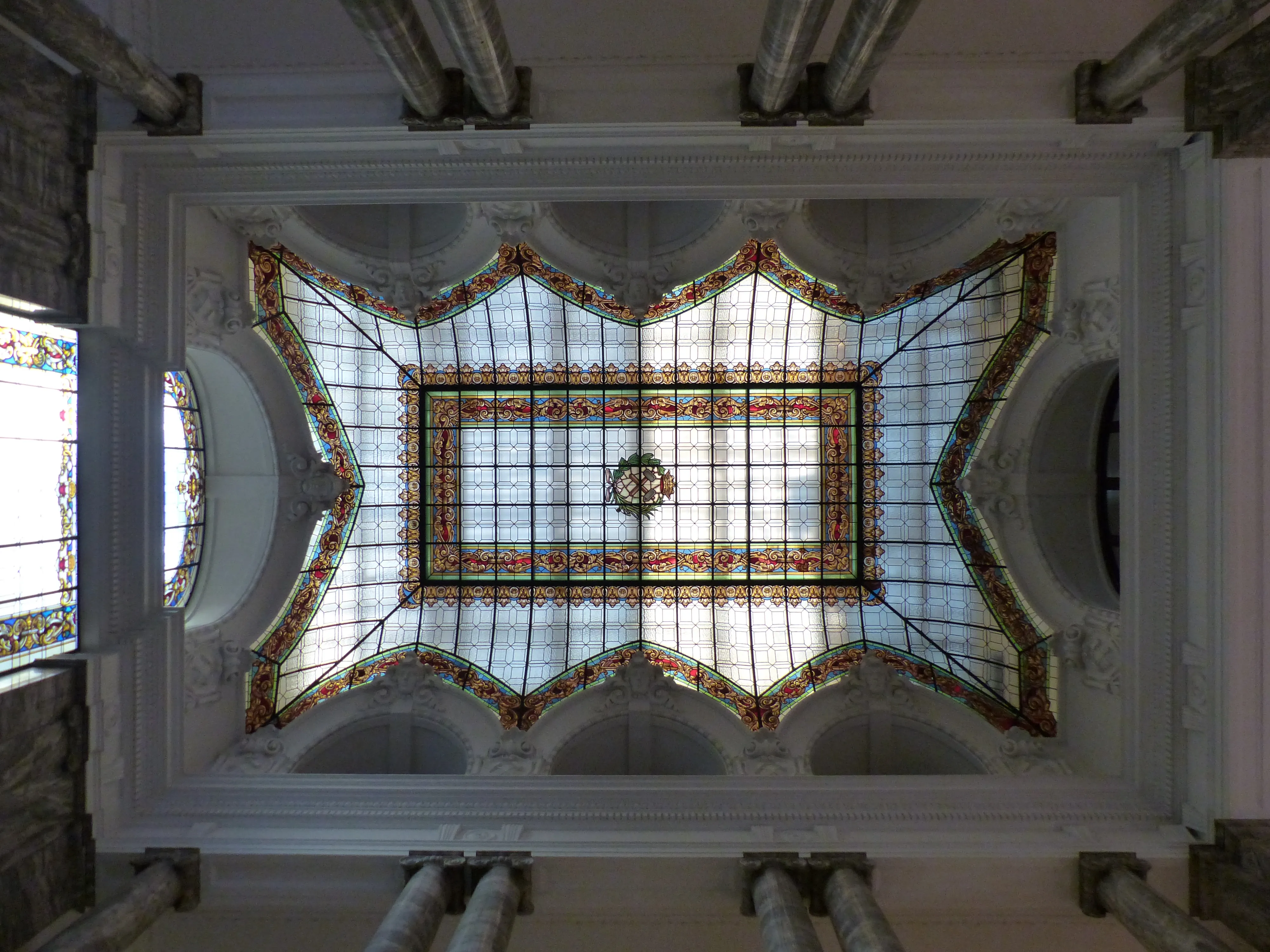 Glas-in-loodplafond met geometrische patronen en een centraal circulair motief in een museuminterieur