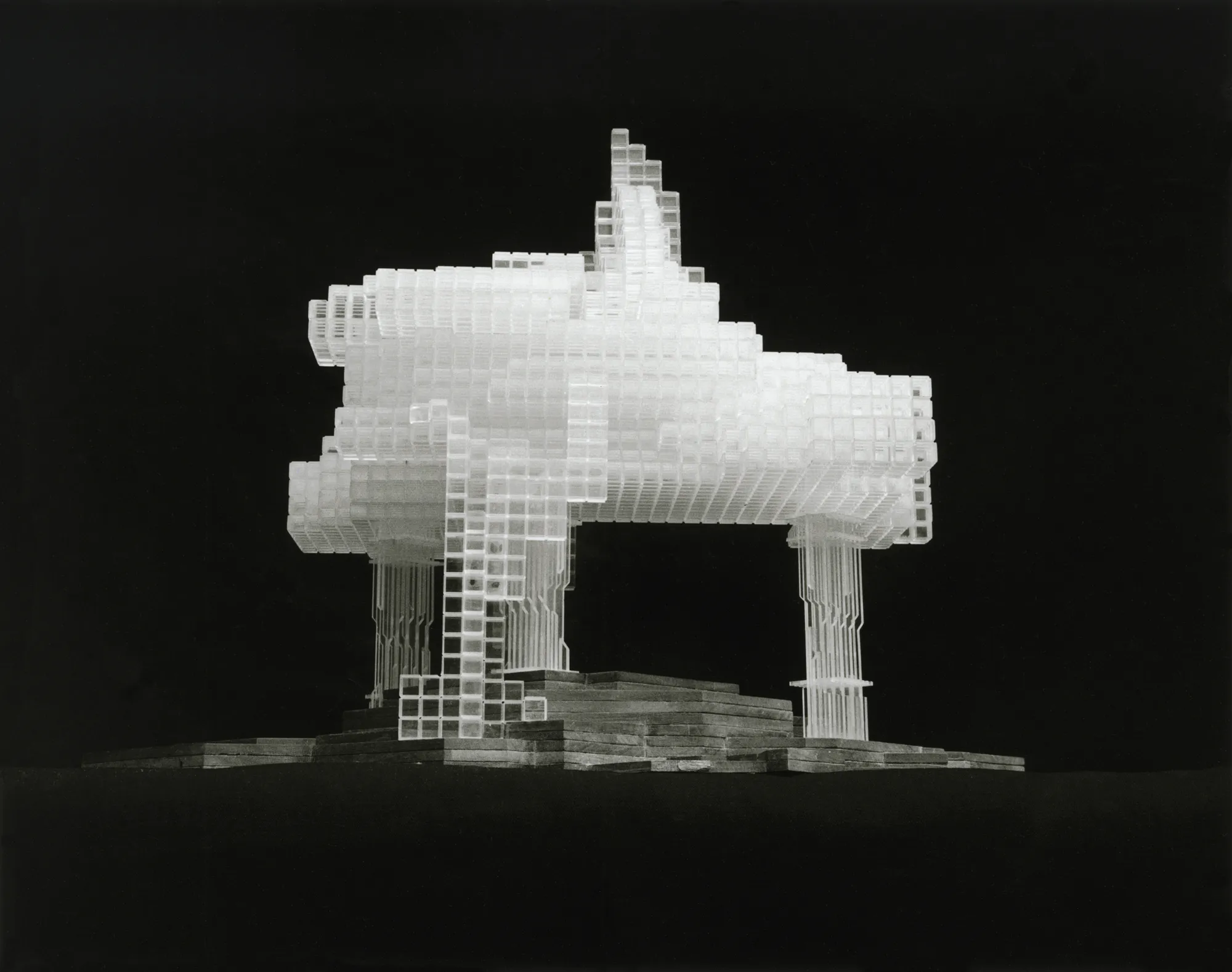 Wit architectuurmodel van een gebouw met een complexe, gelaagde structuur op een donkere achtergrond