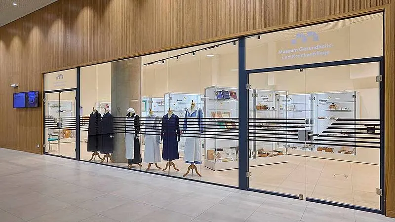 modern glass facade of the Museum of Health and Nursing with mannequins in historical nursing uniforms displayed inside