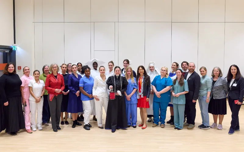Group of people in medical uniforms and formal attire standing in a line inside a modern hall