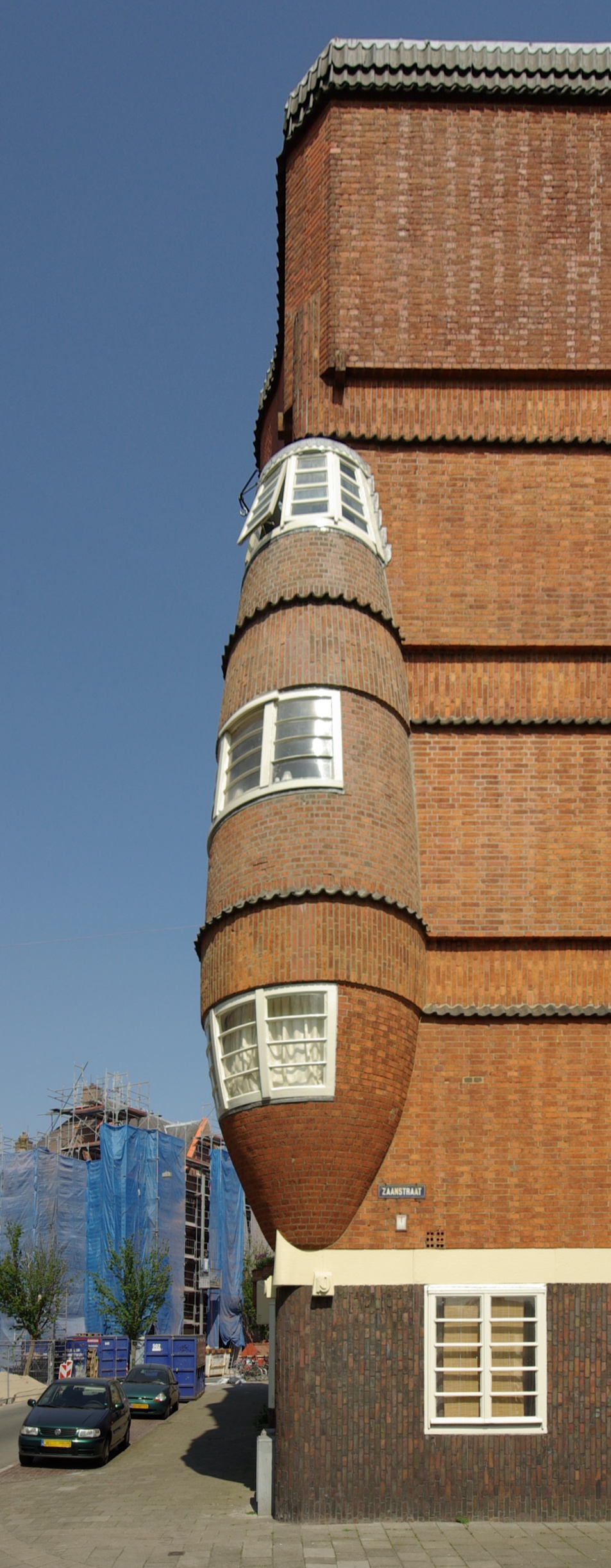 Brick facade of Museum Het Schip with curved architectural details, white-framed windows, and Zaanstraat street sign under a clear blue sky