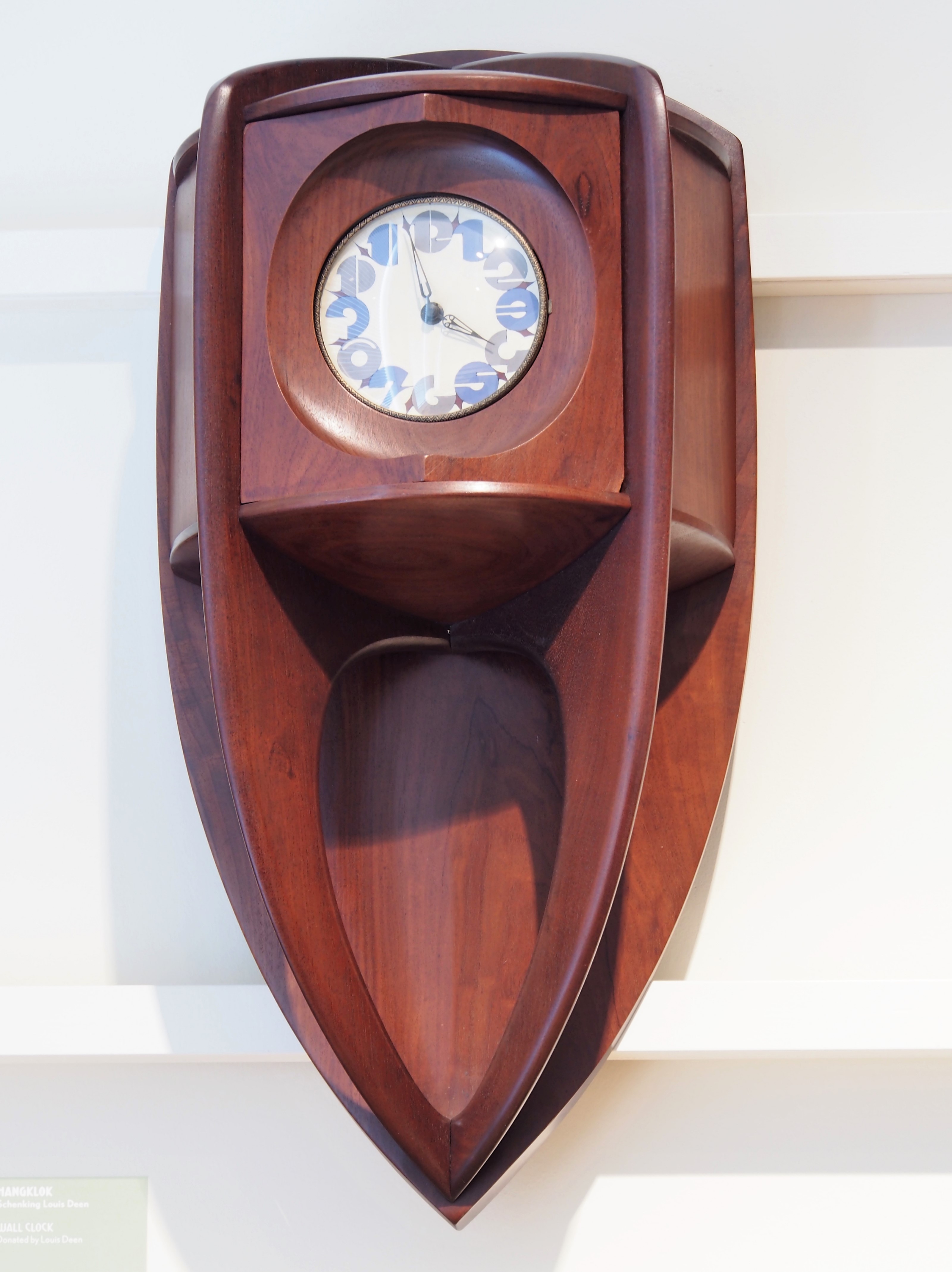 wooden clock with boat-like design and blue and white patterned face