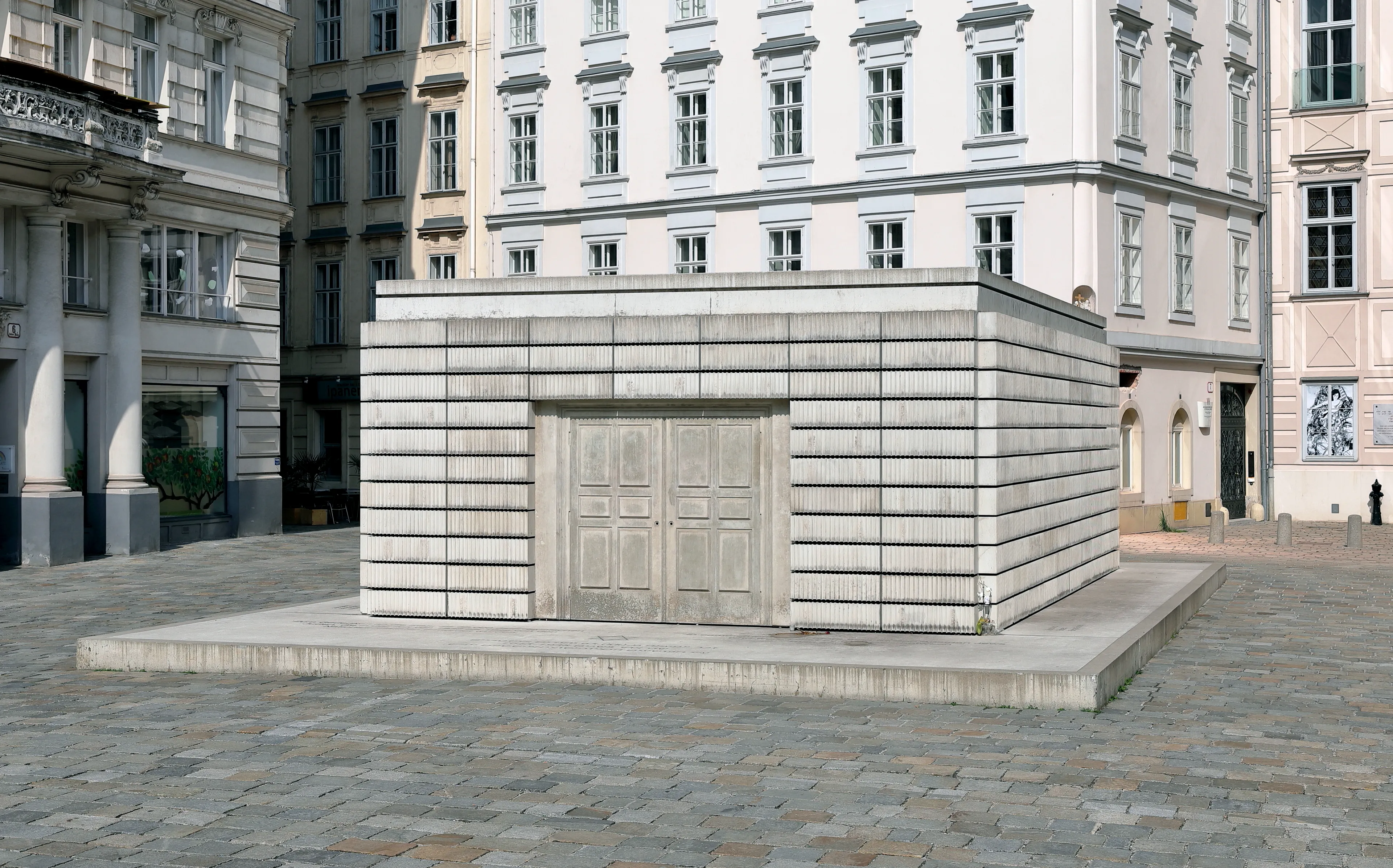 Holocaustmonument op de Judenplatz, een stenen constructie met dubbele deuren, omgeven door bestrate grond en historische gebouwen