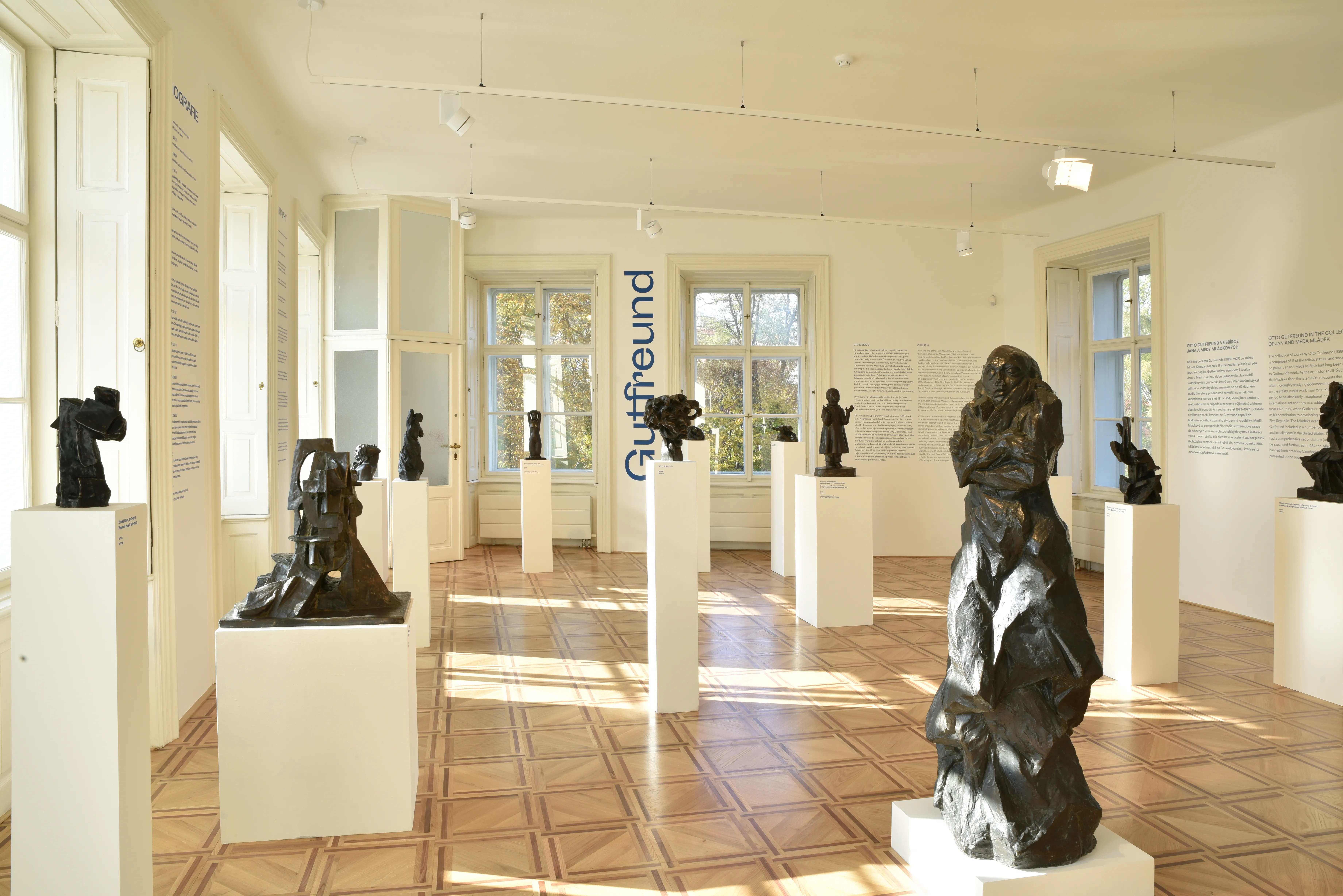Interior del Museo Kampa con esculturas oscuras sobre pedestales blancos en una galería iluminada por el sol