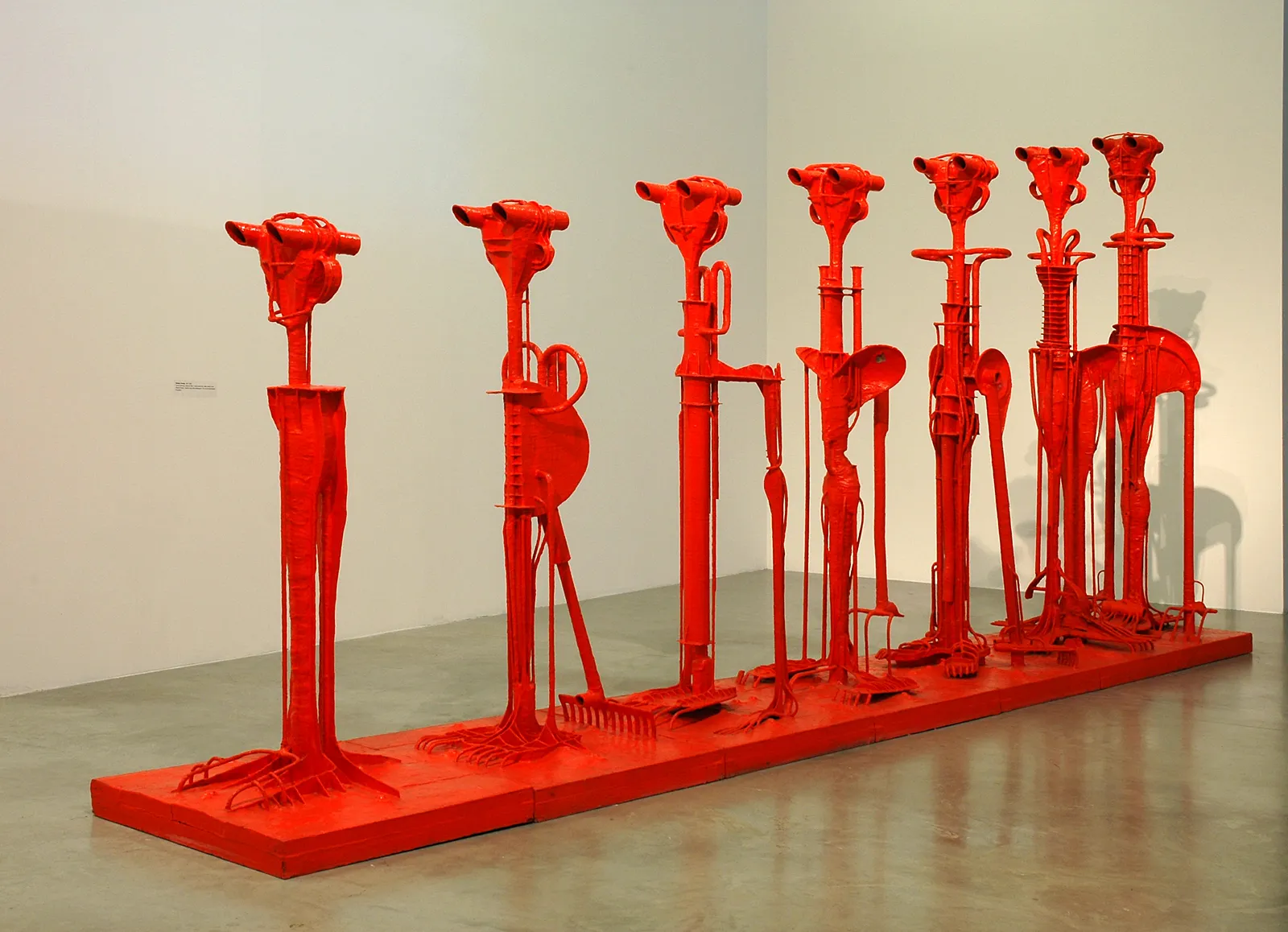 Una hilera de esculturas abstractas rojas sobre una plataforma roja en un espacio de galería