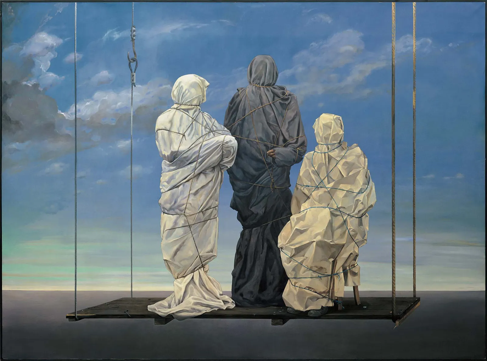 Tres figuras envueltas en tela blanca y oscura se alzan sobre una plataforma contra un cielo azul con nubes