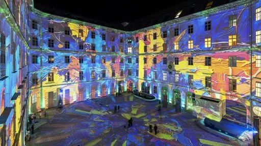 Proyecciones de luz colorida en las paredes del patio de un edificio histórico por la noche