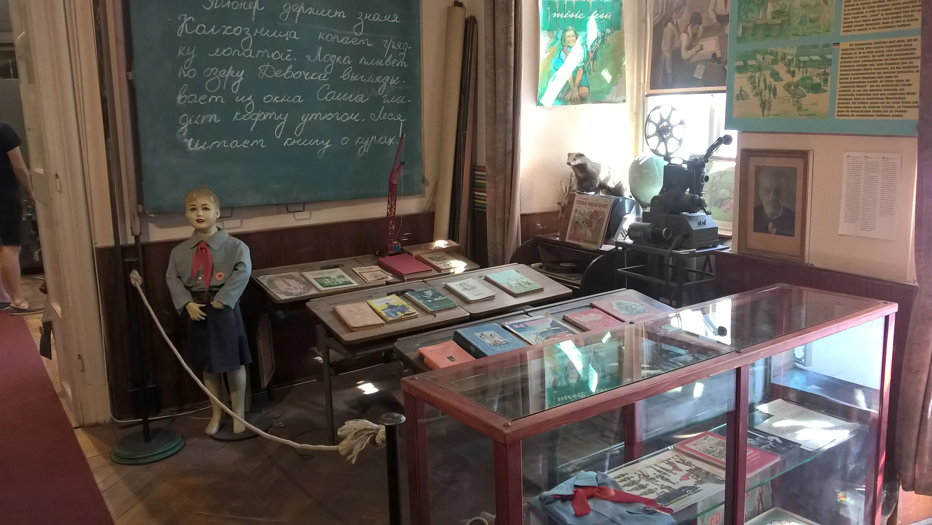 Aula reconstruida con un maniquí de un estudiante, una pizarra y vitrinas con libros y artefactos