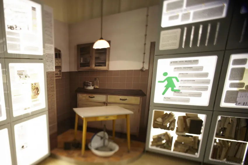 Exhibición con paneles iluminados, una mesa y una maqueta de dispositivo médico en una sala de museo