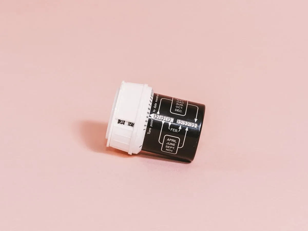 objeto cilíndrico en blanco y negro con diagramas y texto impresos sobre una superficie rosa