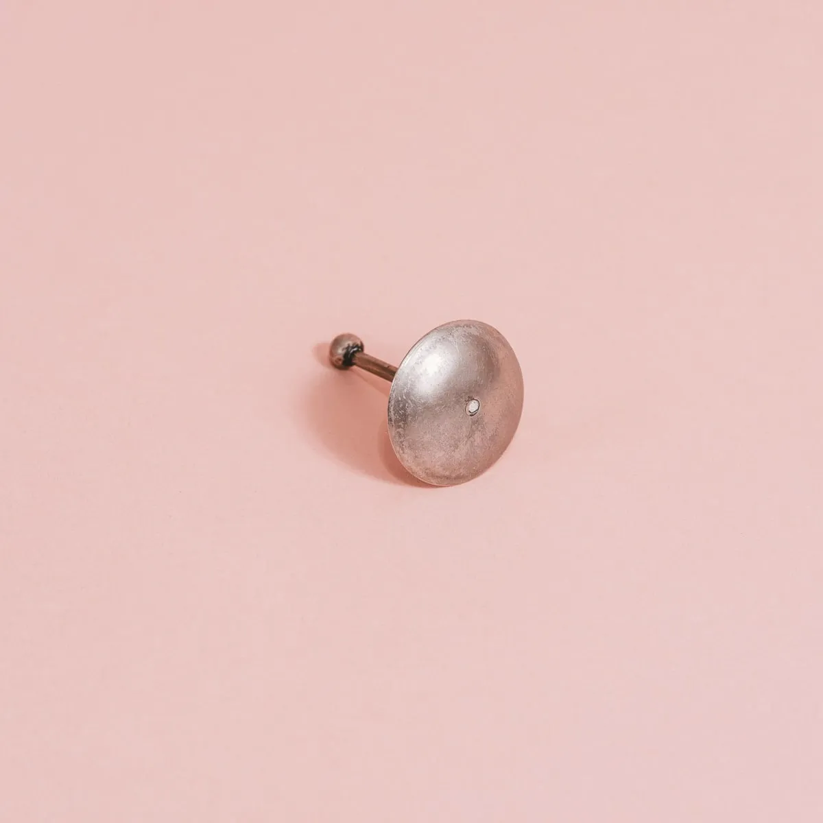 objeto metálico en forma de disco sobre fondo rosa