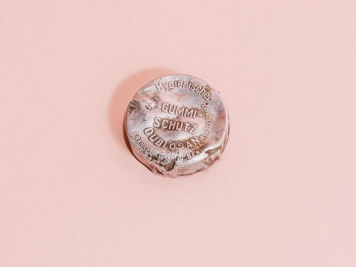 dispositivo anticonceptivo vintage con texto sobre una superficie rosa