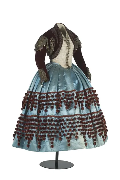 Vestimenta histórica con falda de satén azul claro y chaqueta bordada marrón oscuro en exhibición