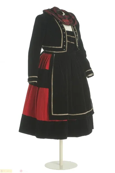 Traje tradicional español con chaqueta de terciopelo negro, detalles rojos y ribete blanco expuesto en un maniquí