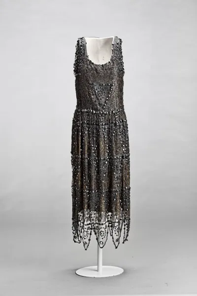 Un vestido negro de cuentas con lentejuelas y detalles de encaje en un maniquí