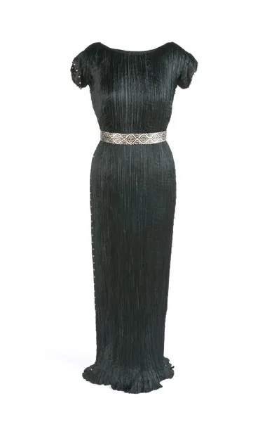Vestido negro plisado con mangas cortas y cinturón plateado en exhibición