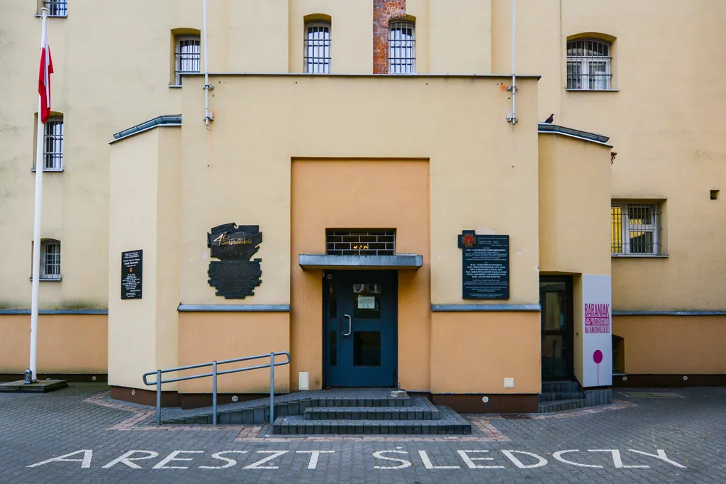 Geel gebouw met een blauwe deur en een bord voor het Museum van Gevleugelde Soldaten en Politieke Gevangenen van de Poolse Volksrepubliek, met een vlaggenmast en een hellingbaan die naar de ingang leidt.