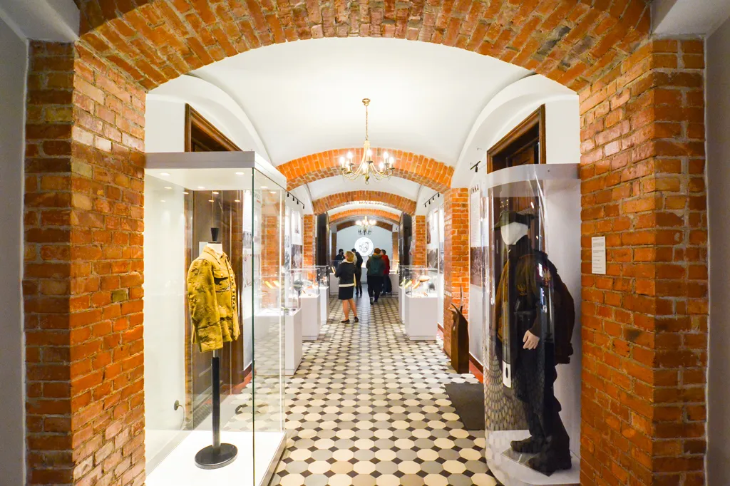Gang met bakstenen bogen en vitrines met artefacten en paspoppen in een museum