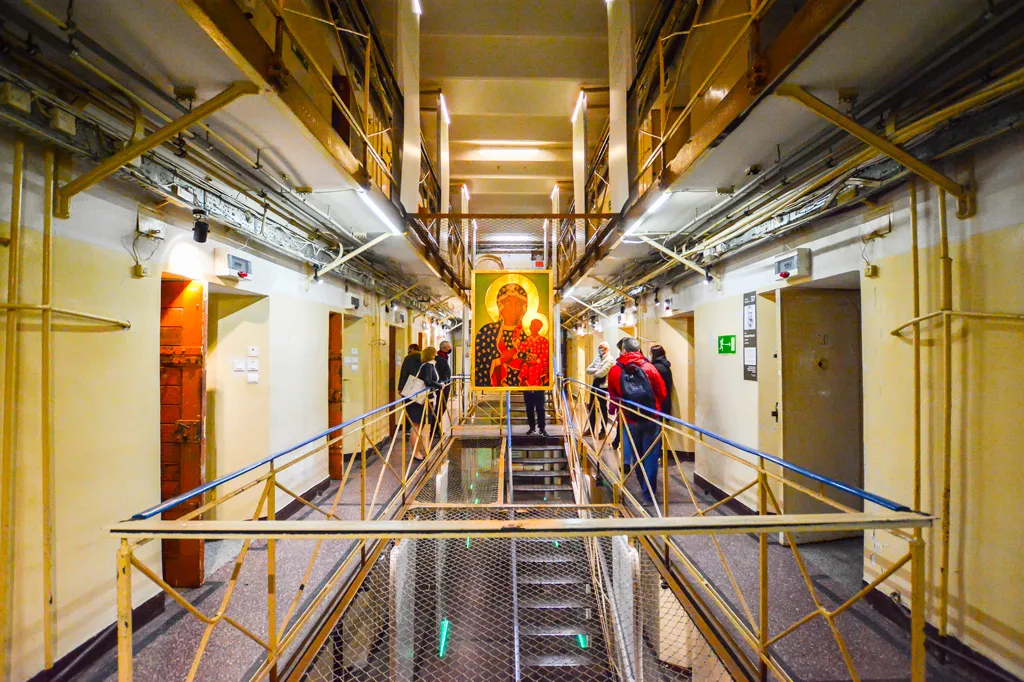 Binnenhal van een museum met gele leuningen, zichtbare leidingen en een religieus icoon aan het einde.