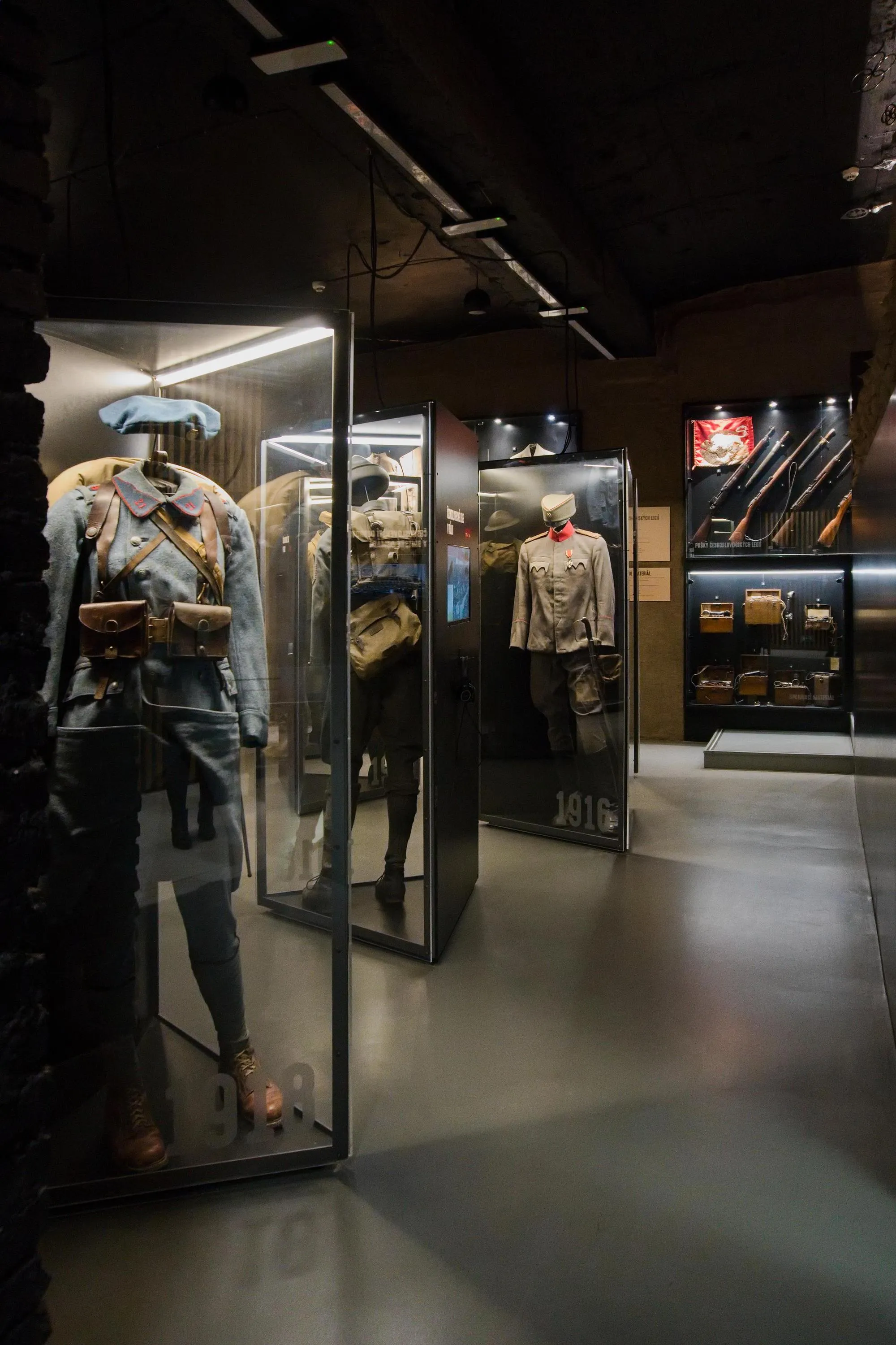 Military uniforms and artifacts displayed in glass cases in a museum gallery