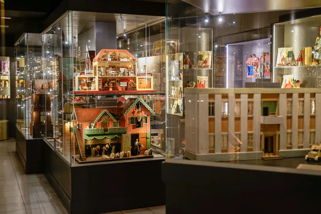 Glass display cases containing detailed dollhouses and miniature rooms