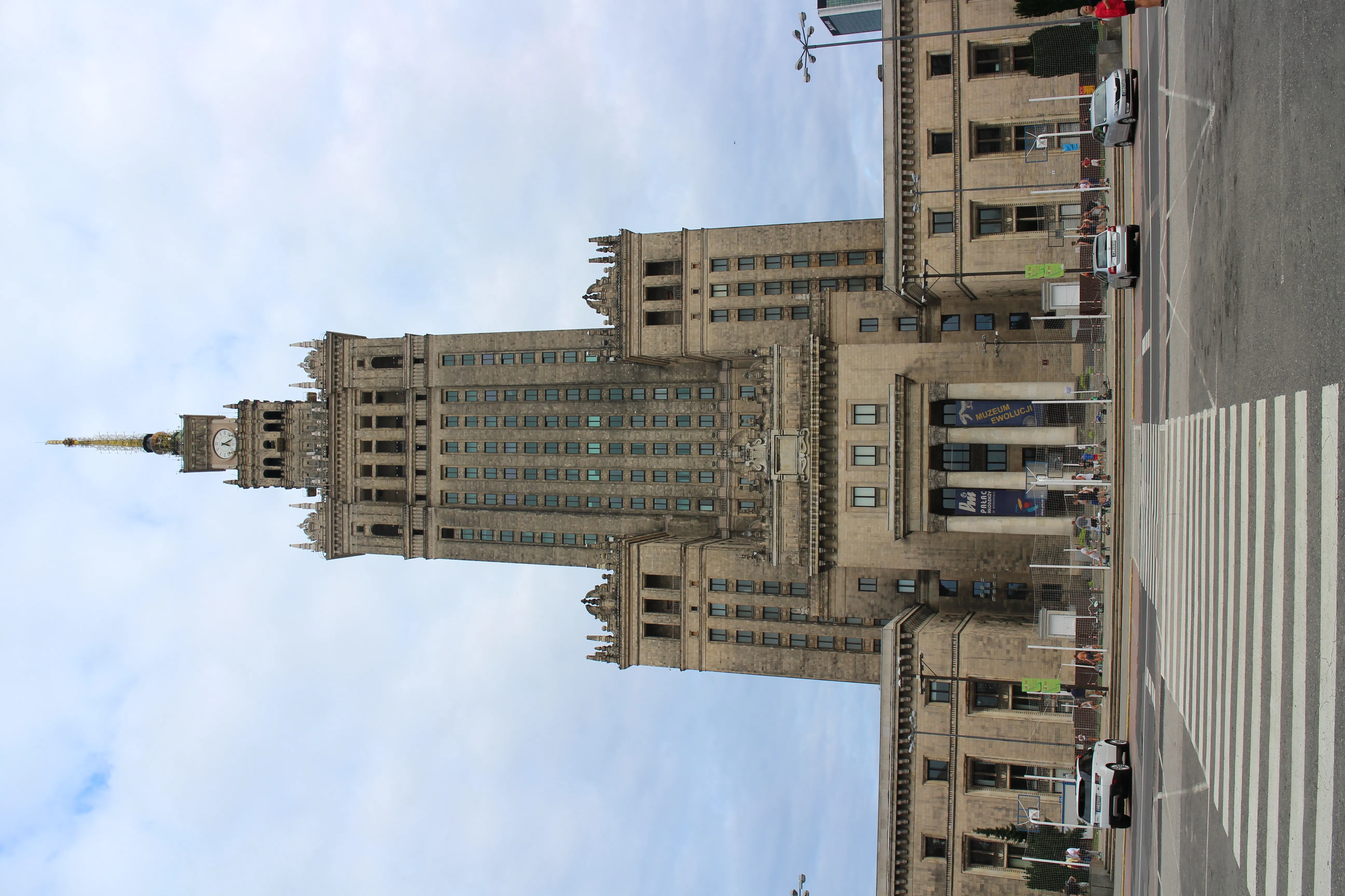 Edificio alto con aguja y arquitectura clásica, visto desde una calle con un cruce peatonal