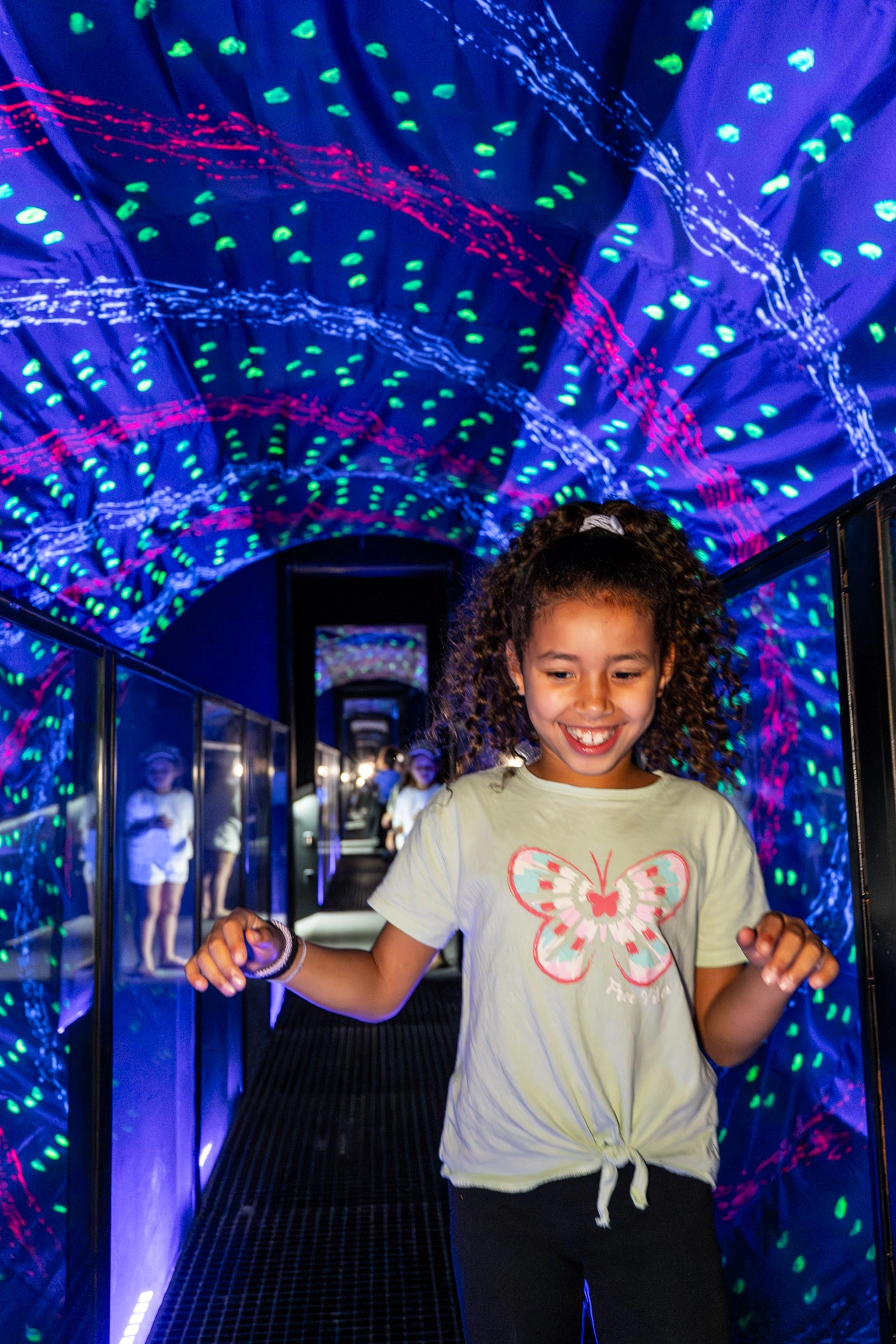 Child experiencing an interactive light tunnel exhibit with colorful LED patterns forming optical illusions at Museum of Illusions Amsterdam