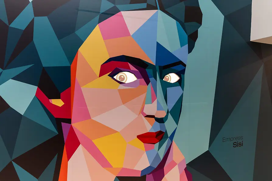 Geometryczny portret twarzy z dużymi oczami, stworzony z kolorowych, wielokątnych kształtów w kolorach niebieskim, żółtym, różowym i czerwonym.