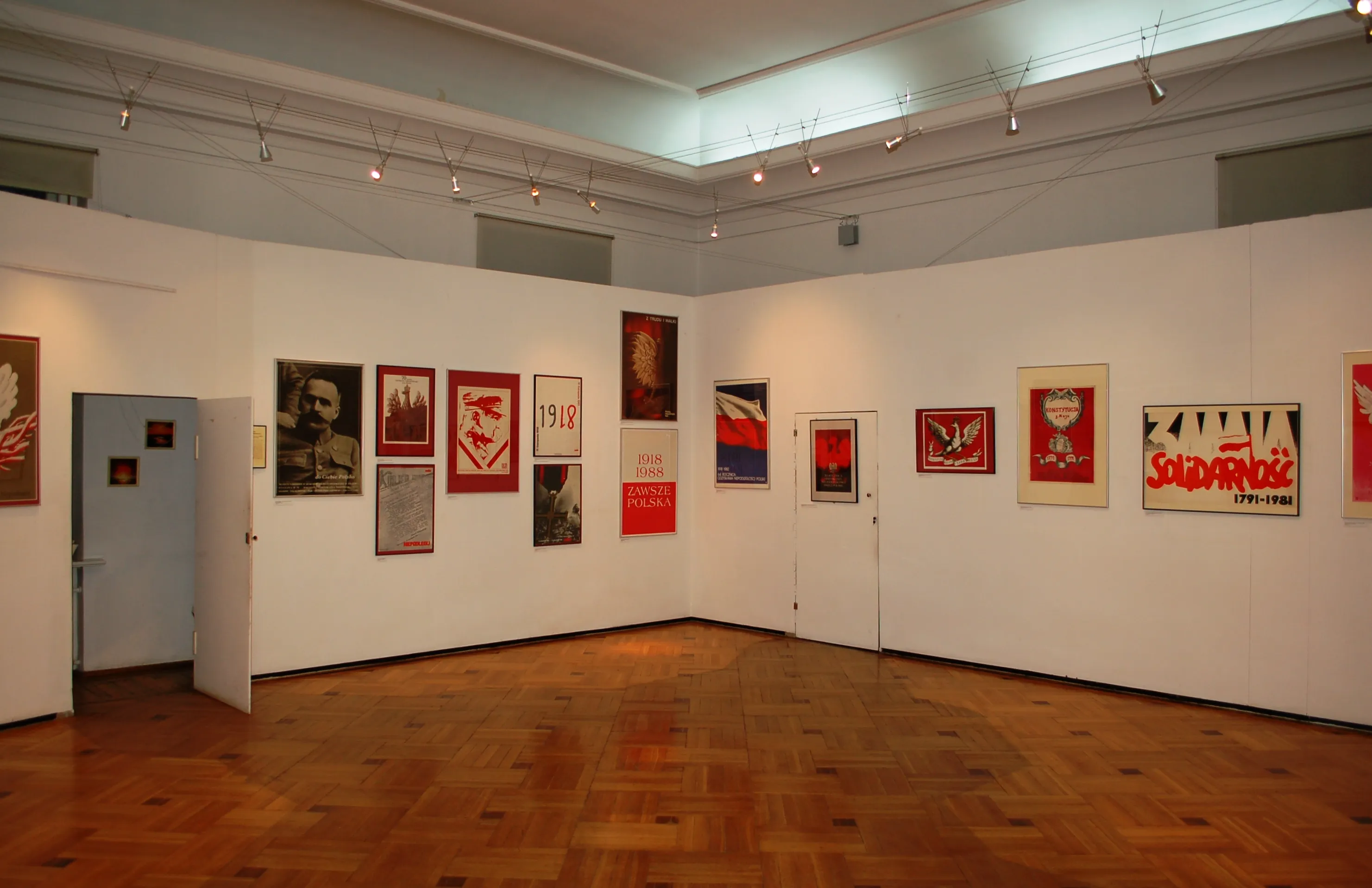 galerie met ingelijste posters aan witte muren en houten vloer