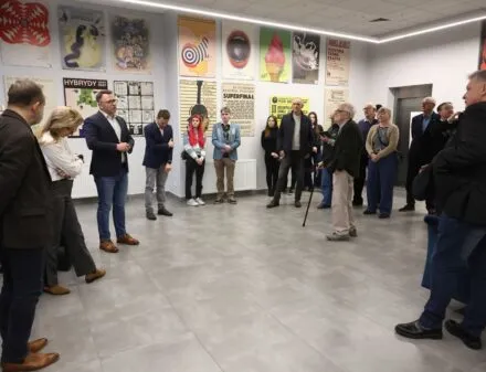 Mensen die in een galerie een collectie posters aan de muren bekijken