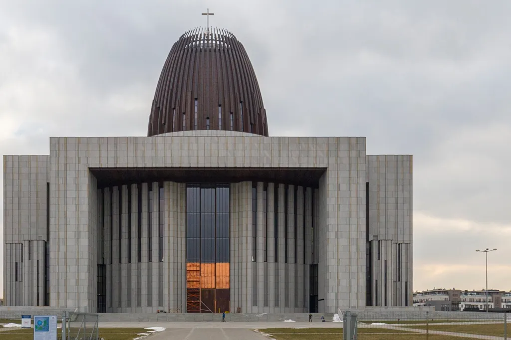 modern gebouw met een grote koepel en kruis erop, voorzien van een betonnen gevel en glazen ingang