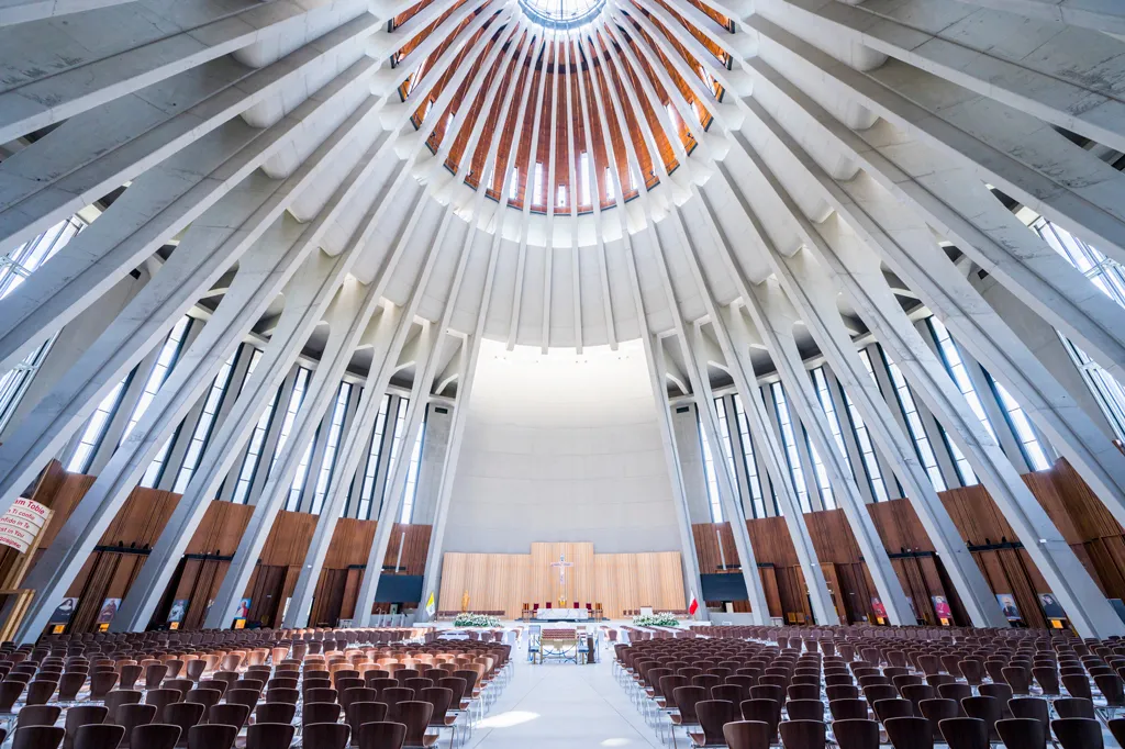 Interieur van een moderne hal met een geribbelde koepel en rijen stoelen