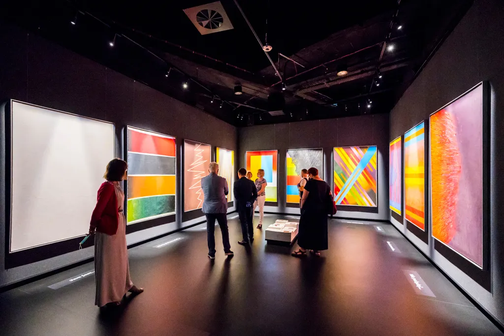 Mensen die abstracte kunstinstallaties bekijken in een museumgalerij met donkere muren en spots