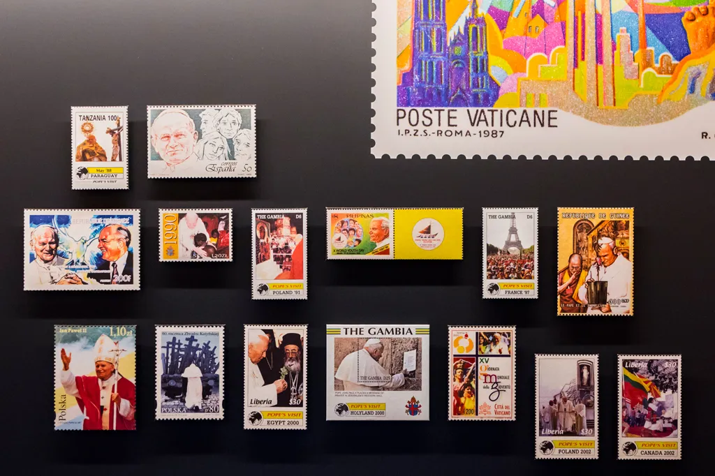 Een verzameling Vaticaanse postzegels met Paus Johannes Paulus II en Kardinaal Stefan Wyszyński, tentoongesteld op een donkere muur