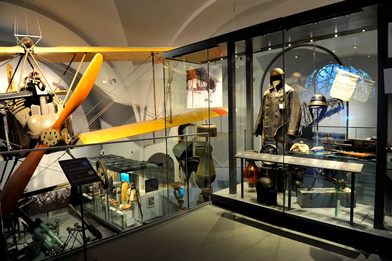 Een vintage Albatros BII-tweevleugelig vliegtuig met een gele vleugel en een militair uniform in een vitrine in een museum.