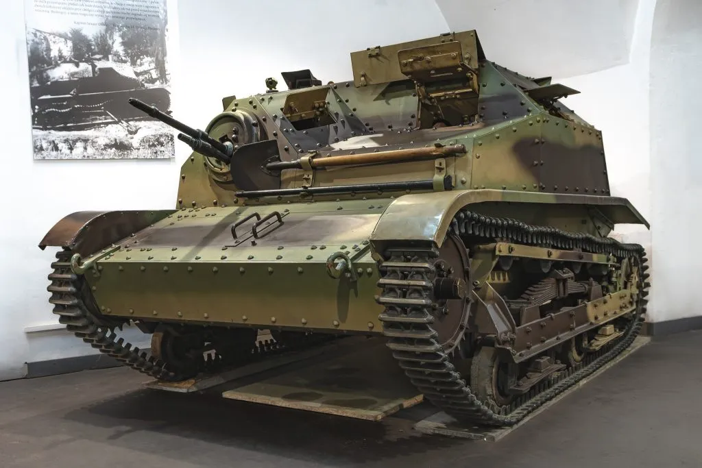 Een groene militaire tank met rupsbanden en een koepel, tentoongesteld in een gebouw