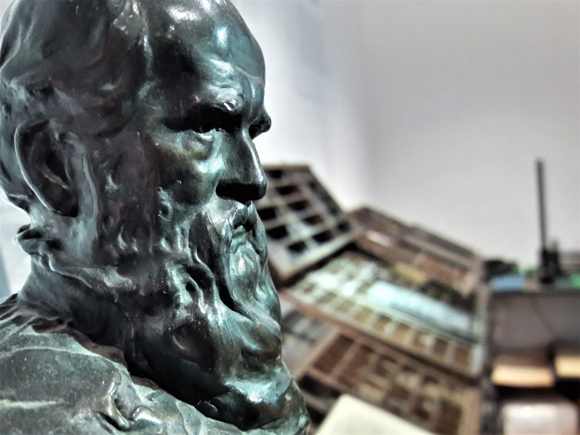 bronze bust of a bearded man with printing presses in the background